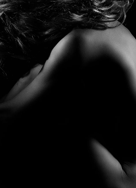 Elegant black and white portrait of a nude woman posing artistically.