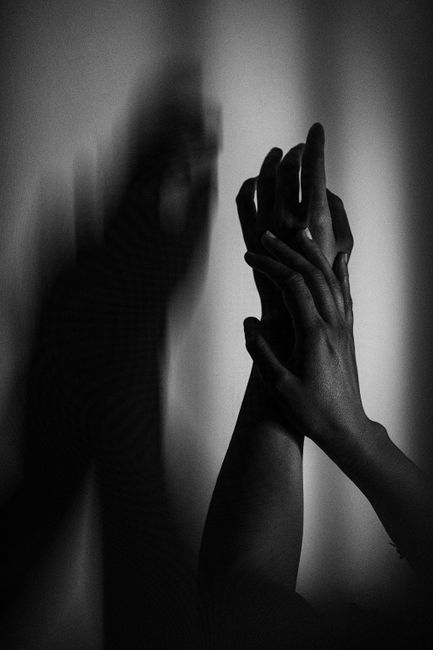 Dramatic black and white photo of hands creating artistic shadows on a wall.
