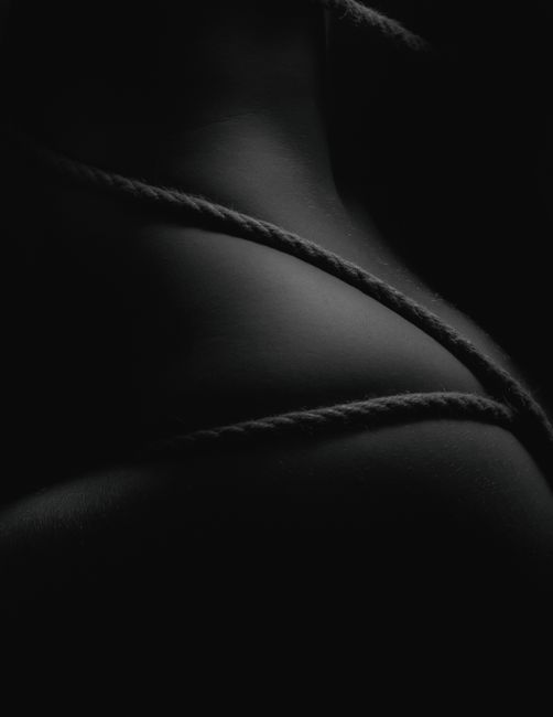 A minimalistic and artistic monochrome image featuring ropes on a dark background in a stu