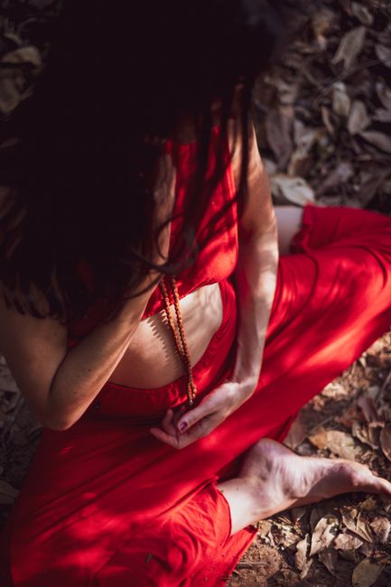 Woman in red dress meditating barefoot outdoors in Belo Horizonte, Brazil.