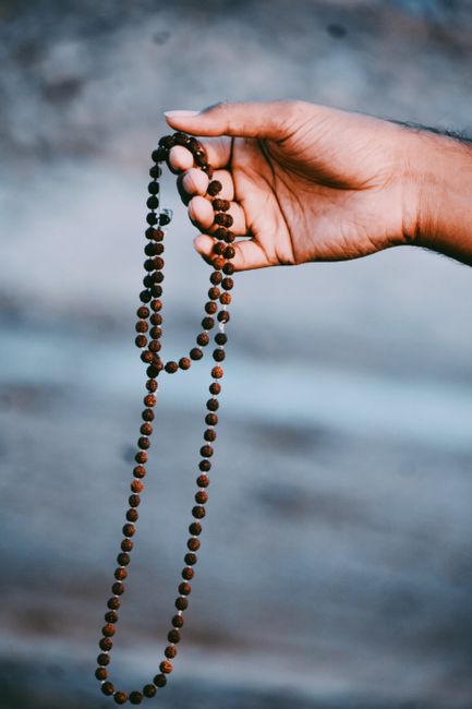 Close-up of a hand holding a Rudraksha bead necklace, symbolizing spirituality and meditat